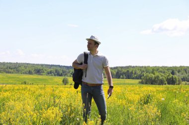 Genç adam bir yaz gününde sırt çantasıyla gezer.