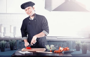 Adam mutfak masasında sebze pişiriyor.