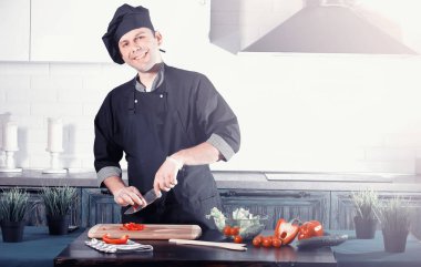 Adam mutfak masasında sebze pişiriyor.