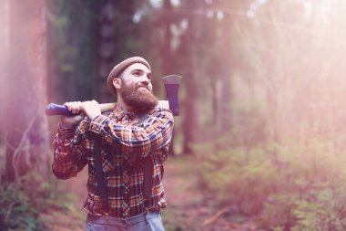 Büyük bir balta ile sakallı bir oduncu ağaç felling önce inceler