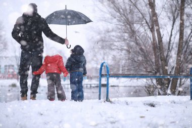 Çocuklar parkta ilk karla yürür.