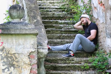 Adam terk edilmiş merdivenlerde oturuyor.