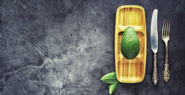 Avokado yemek tarifleri. Tahta kesme tahtasında servis edilen olgun yeşil avokado..