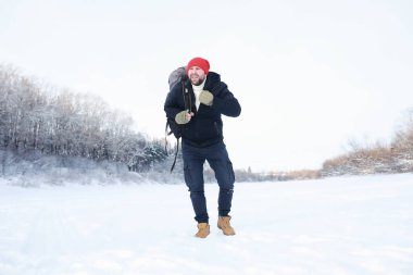 Bir adam sırt çantasıyla seyahat eder. Ormanda kış yürüyüşü. Kışın parkta yürüyüş yapan bir turist..