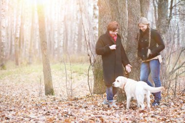 Sonbahar bahçesinde annesiyle köpek gezintisine çıkmış genç bir kız.