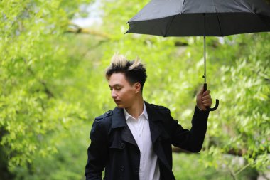 Yağmurlu havada Spring Park ve şemsiyeli genç bir adam. 