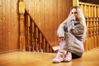 Genç bir kız kazakla merdivende oturuyor.