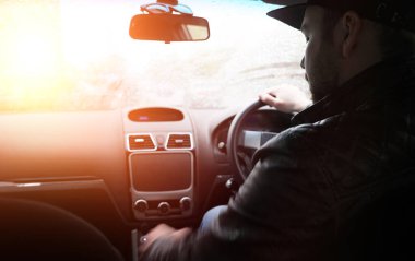 Yağmurlu havada araba sürerken direksiyondaki adam.