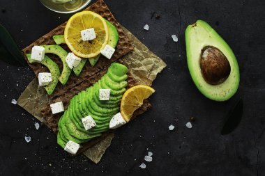 Avokado yemek tarifleri. Tahta kesme tahtasında servis edilen olgun yeşil avokado..