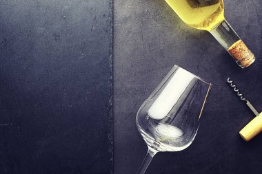 Masada bir bardak kırmızı şarap. Siyah şişe ve bir bardak şarap..