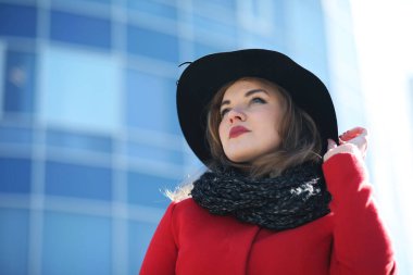 Gökdelenin arka planına karşı kırmızı ceketli hoş bir iş kadını.