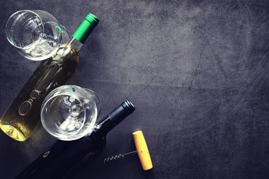 Masada bir bardak kırmızı şarap. Siyah şişe ve bir bardak şarap..