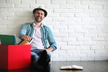 Odadaki genç öğrenci kitaptan gazete okuyor.