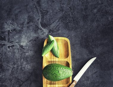 Avokado yemek tarifleri. Tahta kesme tahtasında servis edilen olgun yeşil avokado..