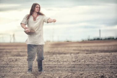 İskandinav görünüşlü genç bir köylü grai ile alan ekiyor