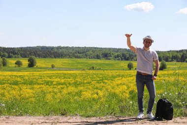 Genç adam bir yaz gününde sırt çantasıyla gezer.