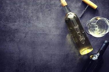 Masada bir bardak kırmızı şarap. Siyah şişe ve bir bardak şarap..