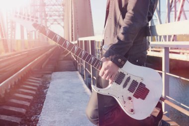 Bir elektro gitar demiryolu üzerinde olan bir adam. Organize sanayi bölgesinde sokakta bir gitar ile deri ceketli bir müzisyen. Köprüde gitarist