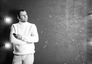 Beyaz kazaklı bir adam karanlık bir odada Musi dinliyor.