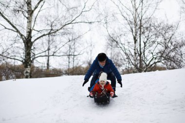 Kışın parktaki çocuklar. Çocuklar parkta karla oynarlar. Kardan adam heykeli yapıp tepelerden aşağı kayıyorlar..