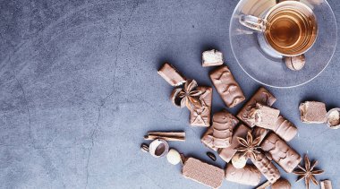 Arkaplanda siyah arka planda çikolatalar. Doldurulmuş çikolata. Atıştırmalık tatlı ve çay.