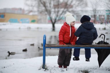 Kışın parktaki çocuklar sno ile oynarlar.