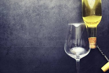 Masada bir bardak kırmızı şarap. Siyah şişe ve bir bardak şarap..