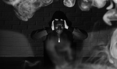 Siyah maskeli ve başlıklı bilgisayar korsanı Monito 'nun önündeki masada.