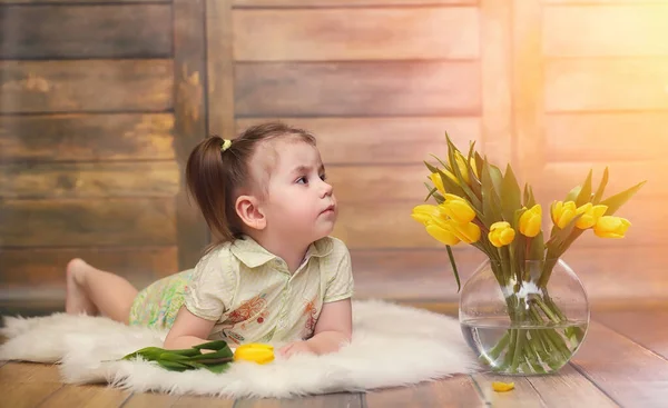 一个带着一束黄色郁金香的小孩子 花瓶里有鲜花的男孩 女孩的礼物在女性假日与黄色郁金香在地板上 — 图库照片