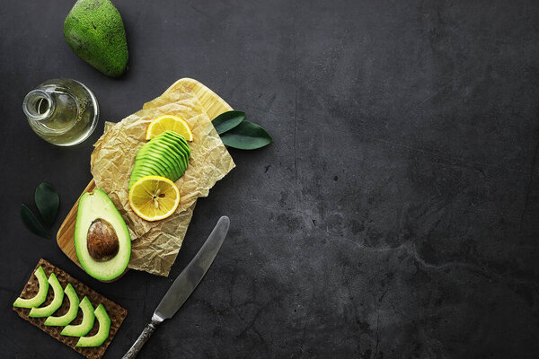 Avocado cooking recipes. Ripe green avocado on a wooden cutting board serving.