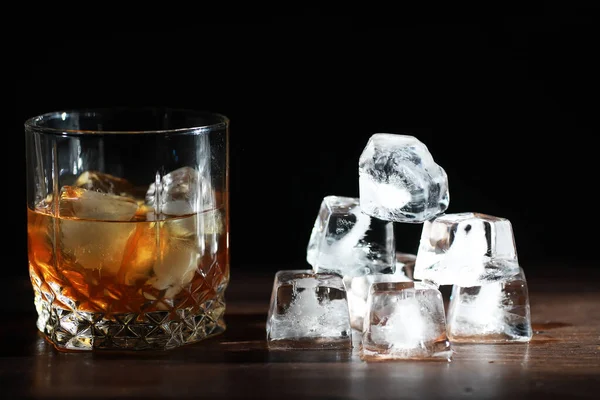 木製のカウンターで氷と強いアルコール飲料のガラス 氷のキューブとウィスキー 冷たい飲み物とガラス — ストック写真