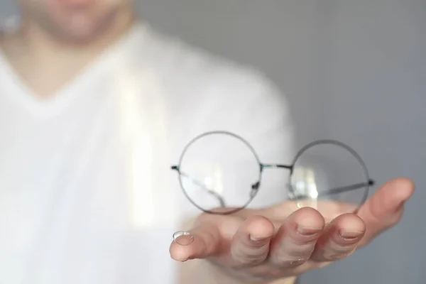 视力差的概念 手拿着隐形眼镜和眼镜 玻璃杯和镜片广告海报 — 图库照片