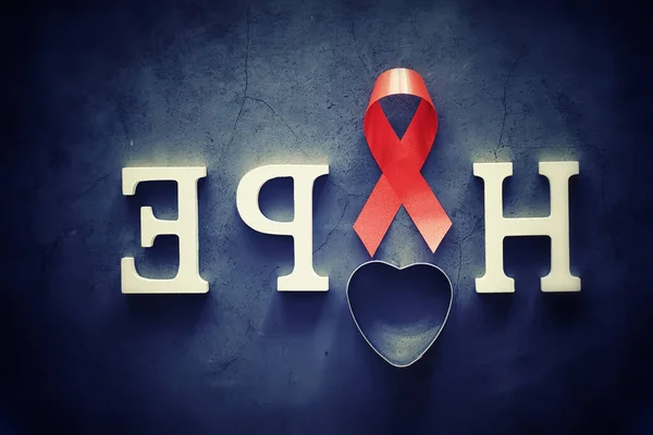 Symbol of human immunodeficiency virus disease. Red ribbon. A helping hand and support. Background.