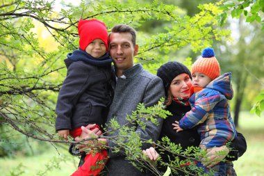 Çocuklu genç bir aile baharda parkta yürüyüşe çıkıyor.