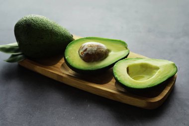 Avokado yemek tarifleri. Tahta kesme tahtasında servis edilen olgun yeşil avokado..