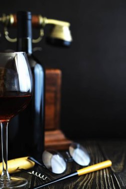 Masada bir bardak kırmızı şarap. Siyah şişe ve bir bardak şarap..