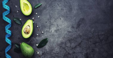 Avokado yemek tarifleri. Tahta kesme tahtasında servis edilen olgun yeşil avokado..