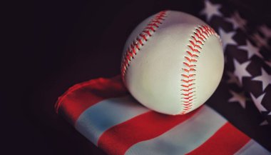Amerikan geleneksel spor oyunu. Beyzbol mu? Kavram. Amerikan bayrağıyla birlikte beyzbol topu ve sopalar masada..