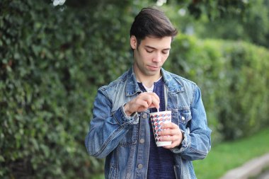 Genç bir adam öğle yemeği zamanında parkta yürür. Bir adam şehirde gezintiye çıktı. Park eden bir öğrenci.