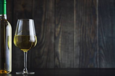 Masada şeffaf beyaz kuru şarap şişesi. Ahşap bir duvar arka plan üzerinde beyaz şarap cam.