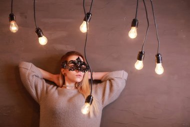 Siyah maskeli, sarı saçlı bir kız.