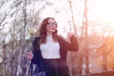 Baharda kız iş kadını dışarıda paltoyla geziyor.