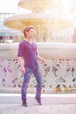 Genç bir adam öğle yemeği zamanında parkta yürür. Bir adam şehirde gezintiye çıktı. Park eden bir öğrenci.