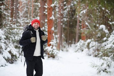 Bir adam sırt çantasıyla seyahat eder. Ormanda kış yürüyüşü. Kışın parkta yürüyüş yapan bir turist..