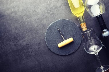 Masada bir bardak kırmızı şarap. Siyah şişe ve bir bardak şarap..