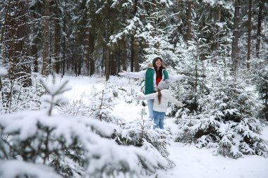 Genç bir aile yürüyüşe çıktı. Anne ve kızı karlı bir parkta yürüyorlar..