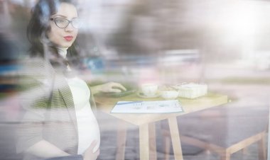 Yemekte kafede bilgisayar başında çalışan hamile bir kadın.