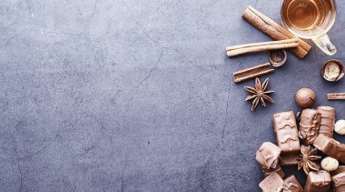 Arkaplanda siyah arka planda çikolatalar. Doldurulmuş çikolata. Atıştırmalık tatlı ve çay.