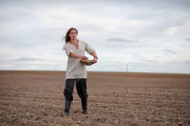 İskandinav görünüşlü genç bir köylü grai ile alan ekiyor