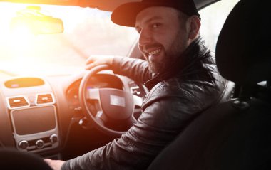 Yağmurlu havada araba sürerken direksiyondaki adam.